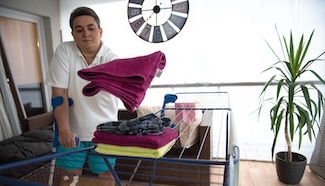 Person managing laundry at home, representing the physical effort each step requires for someone living with a chronic condition or disability