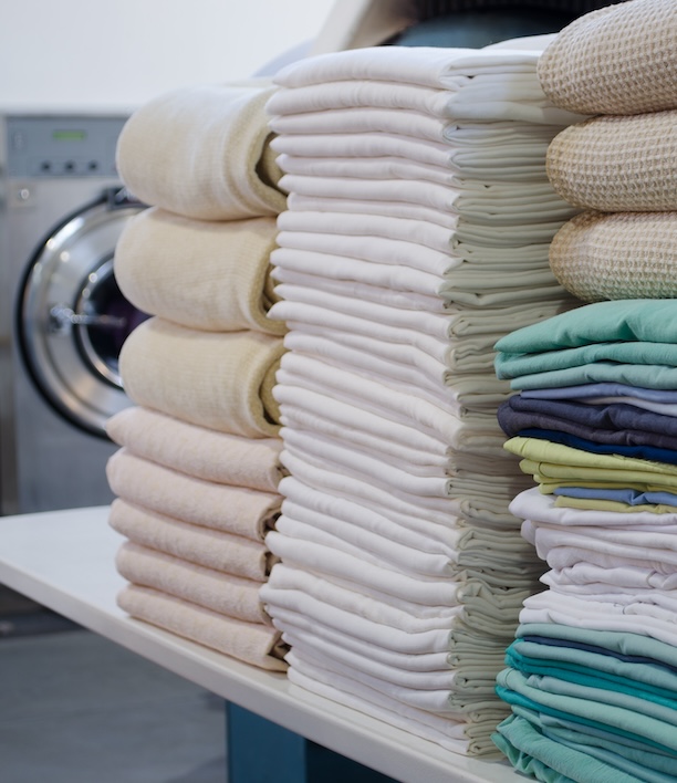 Neatly stacked piles of folded laundry in various colors, representing the end result both options are working toward and the question of which path to get there makes more sense