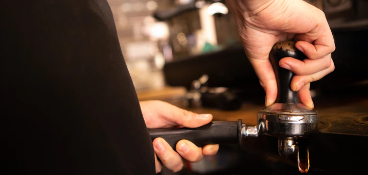 Barista stamping an espresso shot