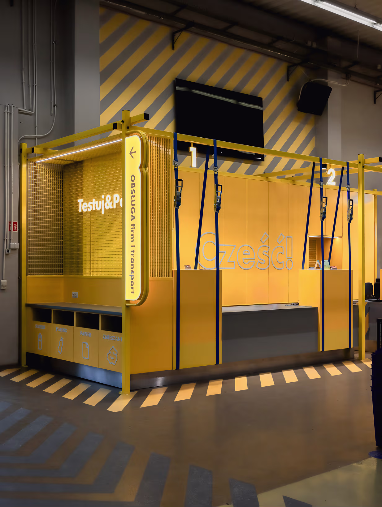 Moduł Testuj&Pakuj obok strefy obsługi klienta z napisem Cześć! i stanowiskami w sklepie HOGER