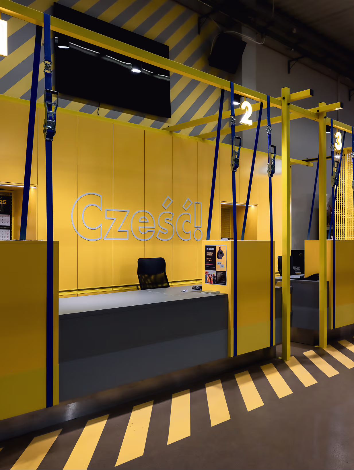 Strefa obsługi HOGER z napisem Cześć!, żółtymi panelami i granatowymi pasami przy stanowiskach 2 i 3