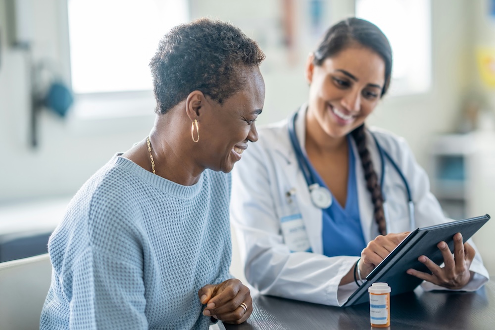 A doctor discusses health concerns with a patient, using the Epocrates app for reference on a mobile device.