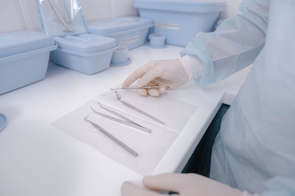 Close-up of dental tools on a table with a dentist in surgical gloves, showcasing a clean healthcare environment.