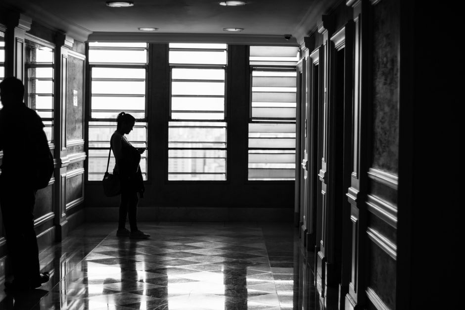Silhouettes in a modern hallway with geometric window patterns.