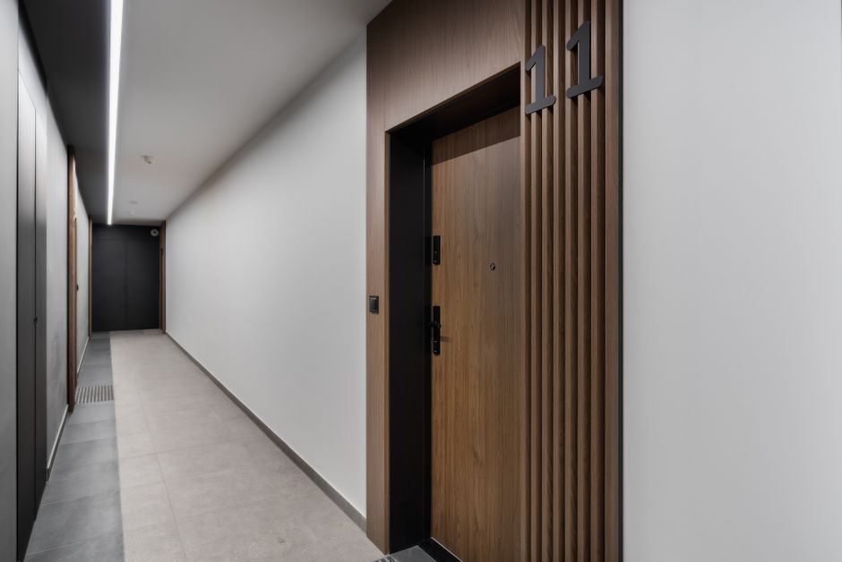 Sleek and modern apartment corridor featuring a wooden door with room number 11 in a minimalist design.