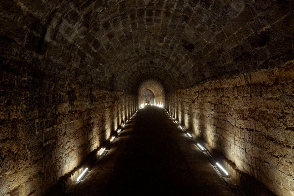 Explore the moody ambience of an illuminated stone tunnel with perspective depth.