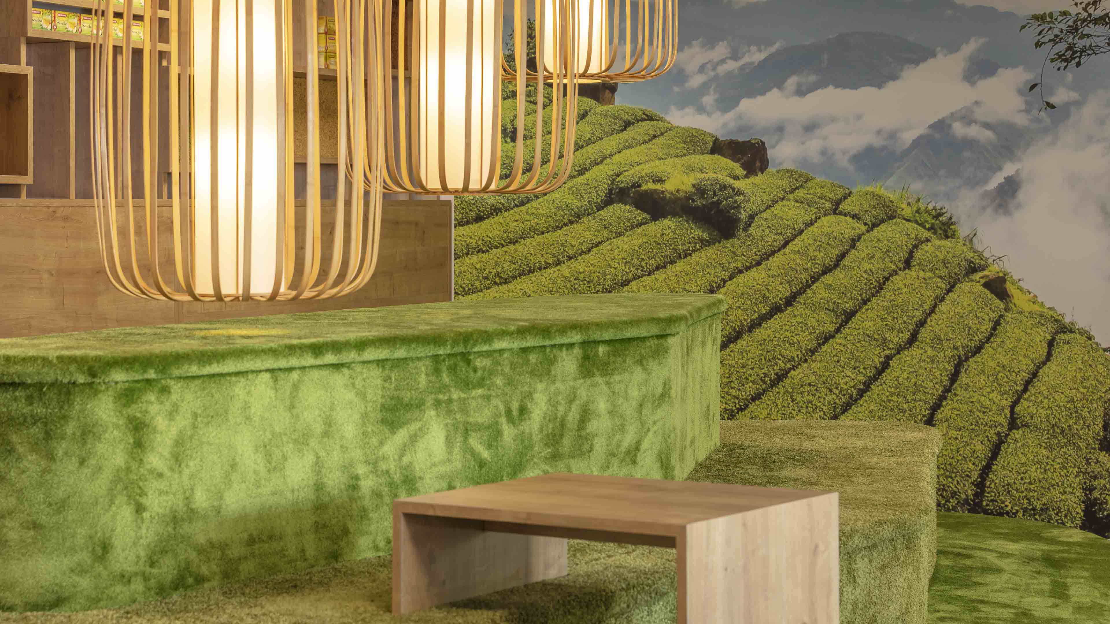 Grüne Sitzstufen imitieren einen Teeberg. Die Gestaltung wird durch Naturholz und eine große Fototapete ergänzt.