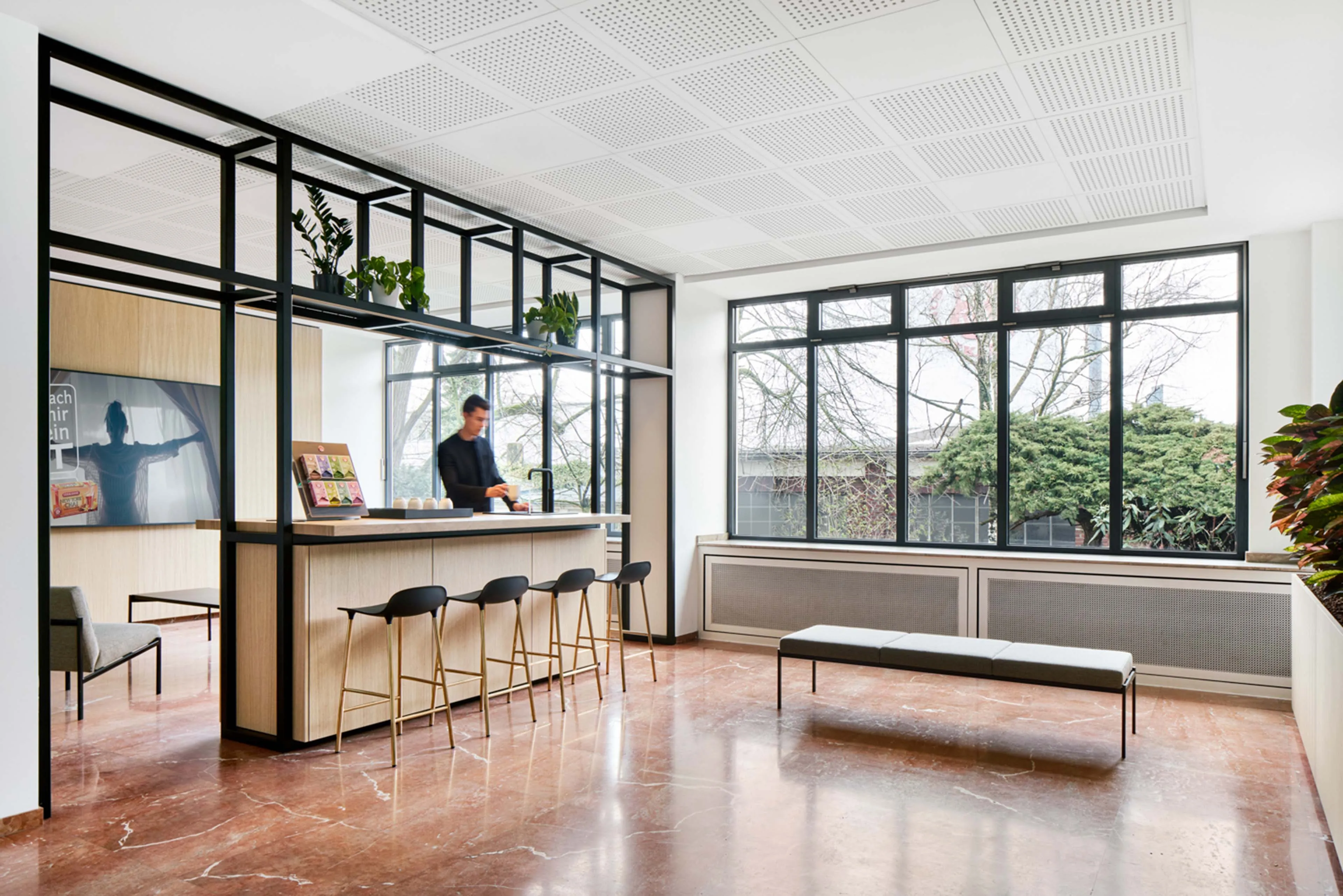 Heller und modern gestalteter Büroraum mit Teeküche und Sitzbereich in hellem Holz.