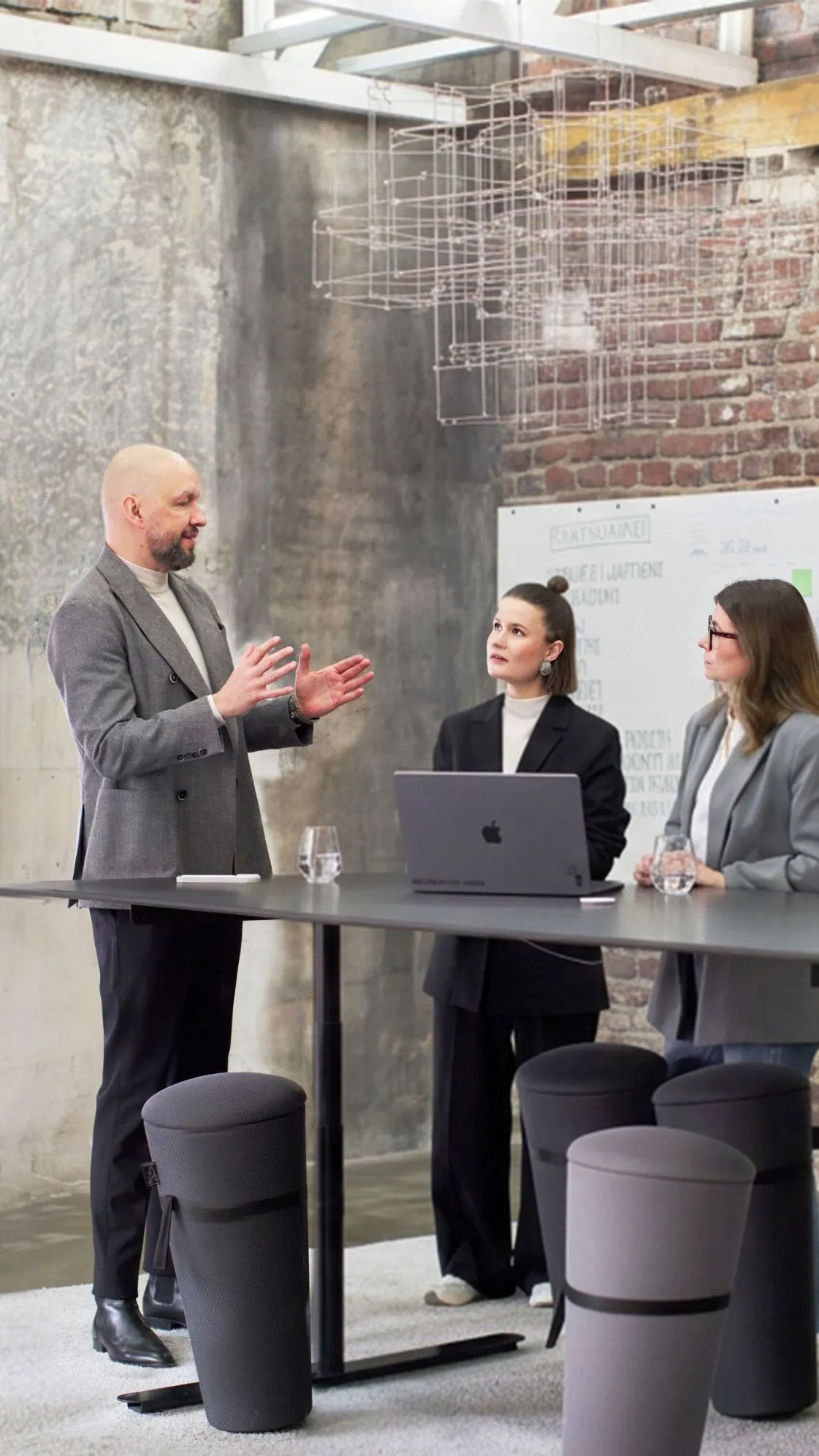Heiner Kolde, Hannah Schwarz und Marie Seliger stehen an einem großen Tisch in einem hellen Besprechungsraum.