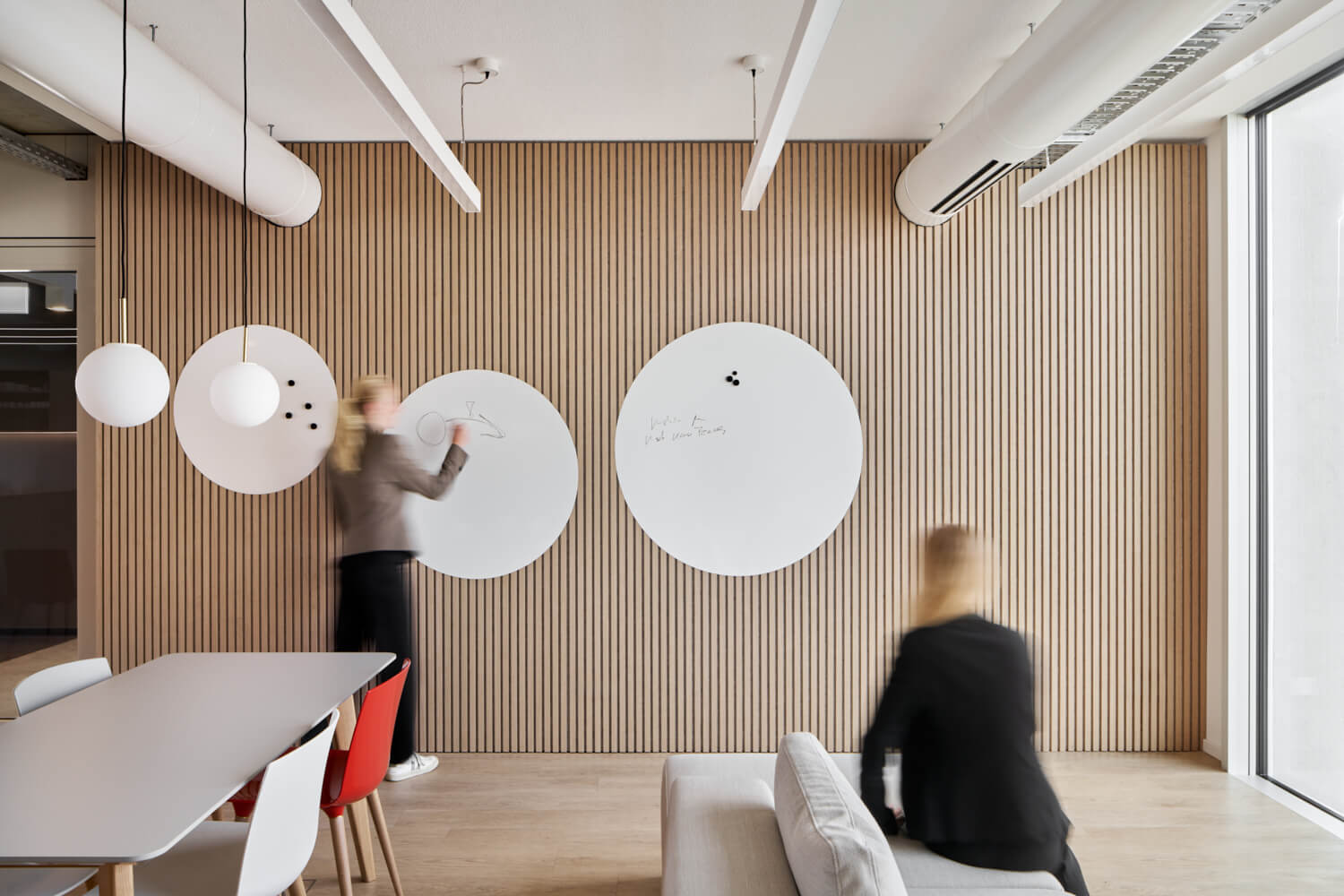 Besprechungssituation in einem flexibel gestaltbarem Raum mit hellen Wandpanelen und zwei Personen in einer Besprechung.