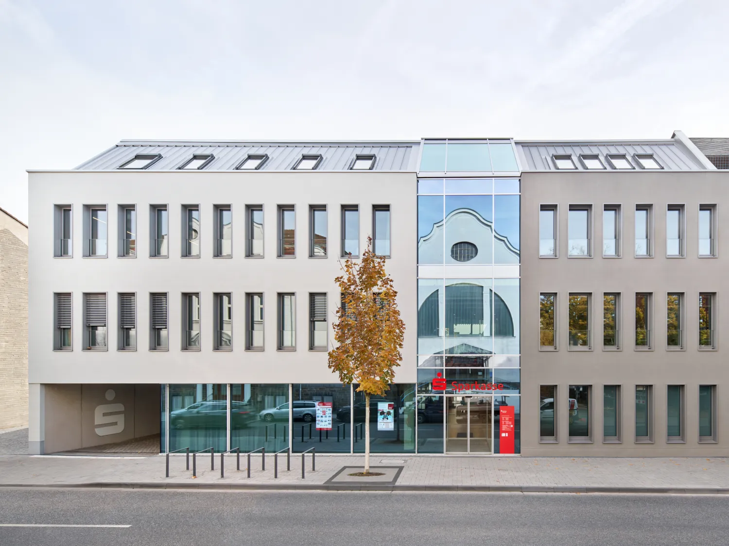 Straßenansicht eines modernen Sparkassen-Gebäudes mit klar gegliederter Fassade und mittigem gläsernen Verbinder.