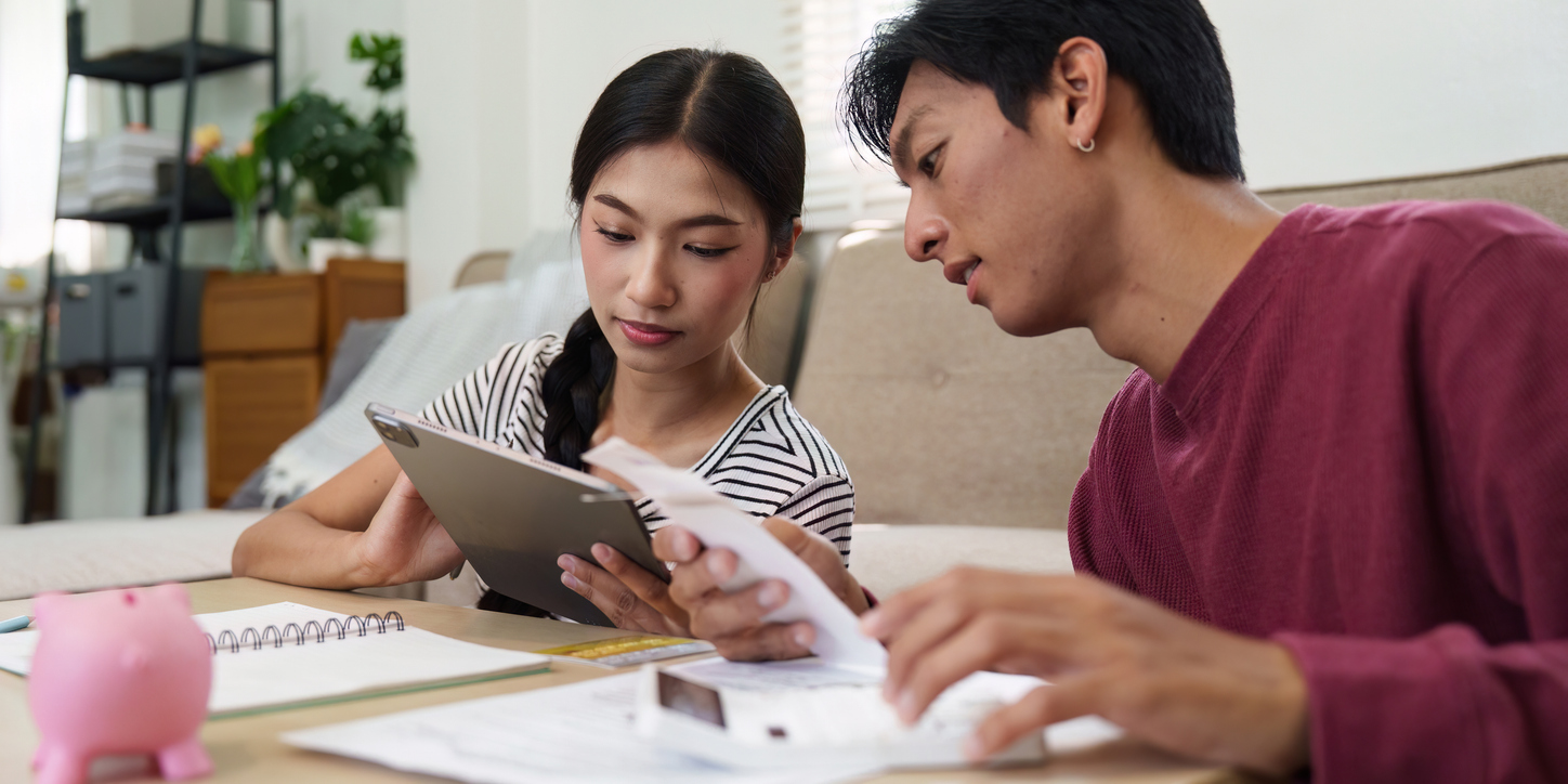Male and female nonprofit leaders work together to come up with a budget in the living room of one of their homes.