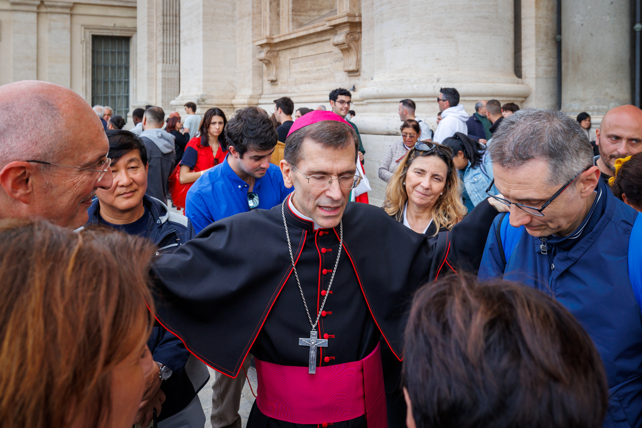 A priest prays with members of his congregation before a charity event.