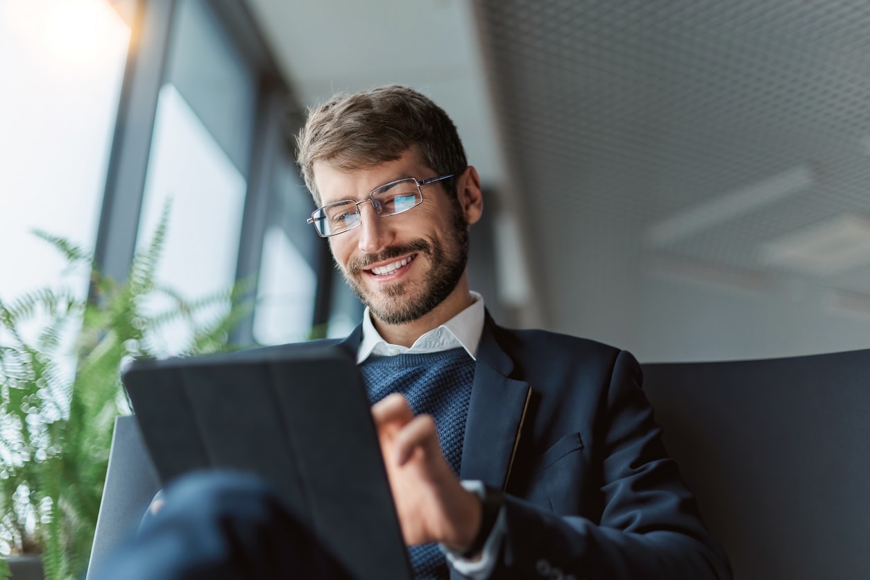 A photo of a businessman smiling as he works on a computer.
