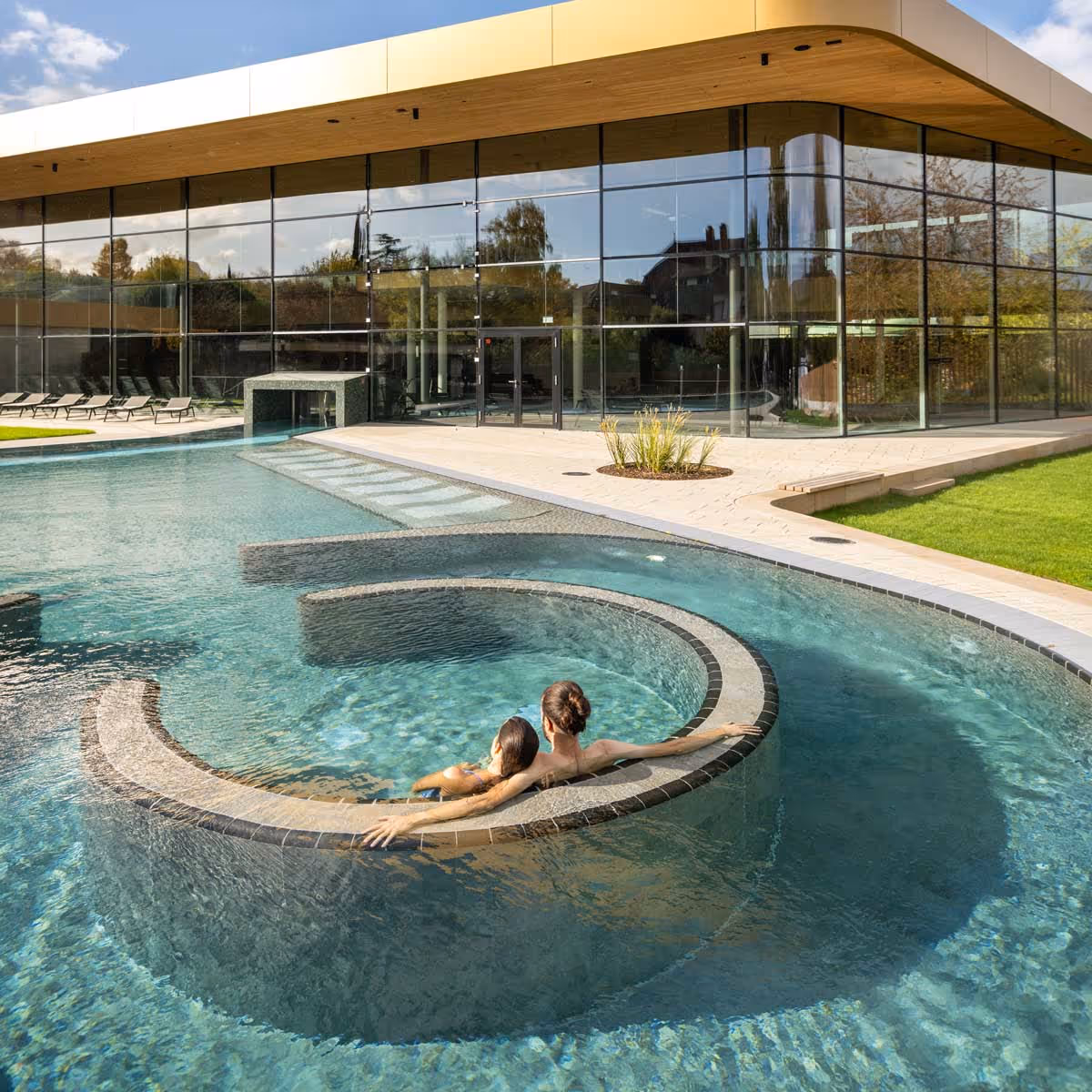 Zwei Personen entspannen in einem runden, spiralförmigen Außenpool der Salinarium Bad Dürkheim Therme