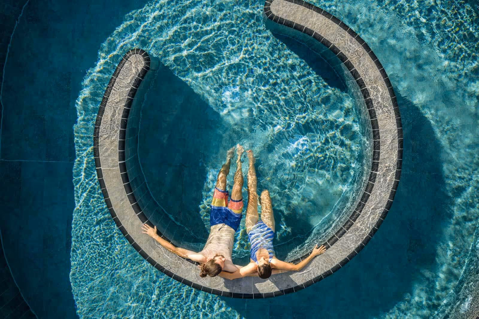 Ein Paar sitzt entspannt in einem runden Pool mit klarem blauem Wasser und genießt die Sonne in der Salinarium Bad Dürkheim Therme