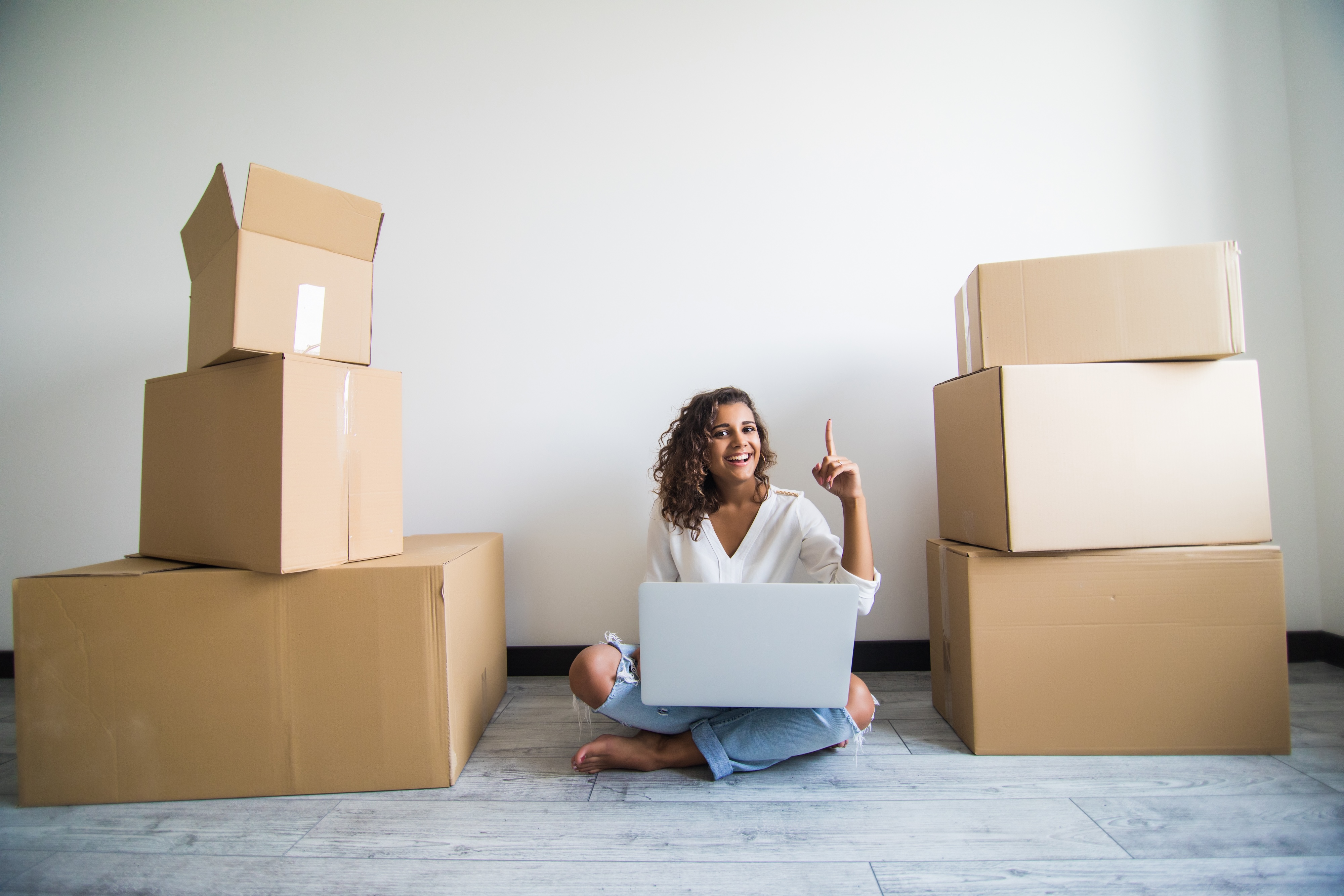 Young woman moving into a new apartment at Wildcat Vista, surrounded by cardboard boxes and using a laptop to organize her move-in day