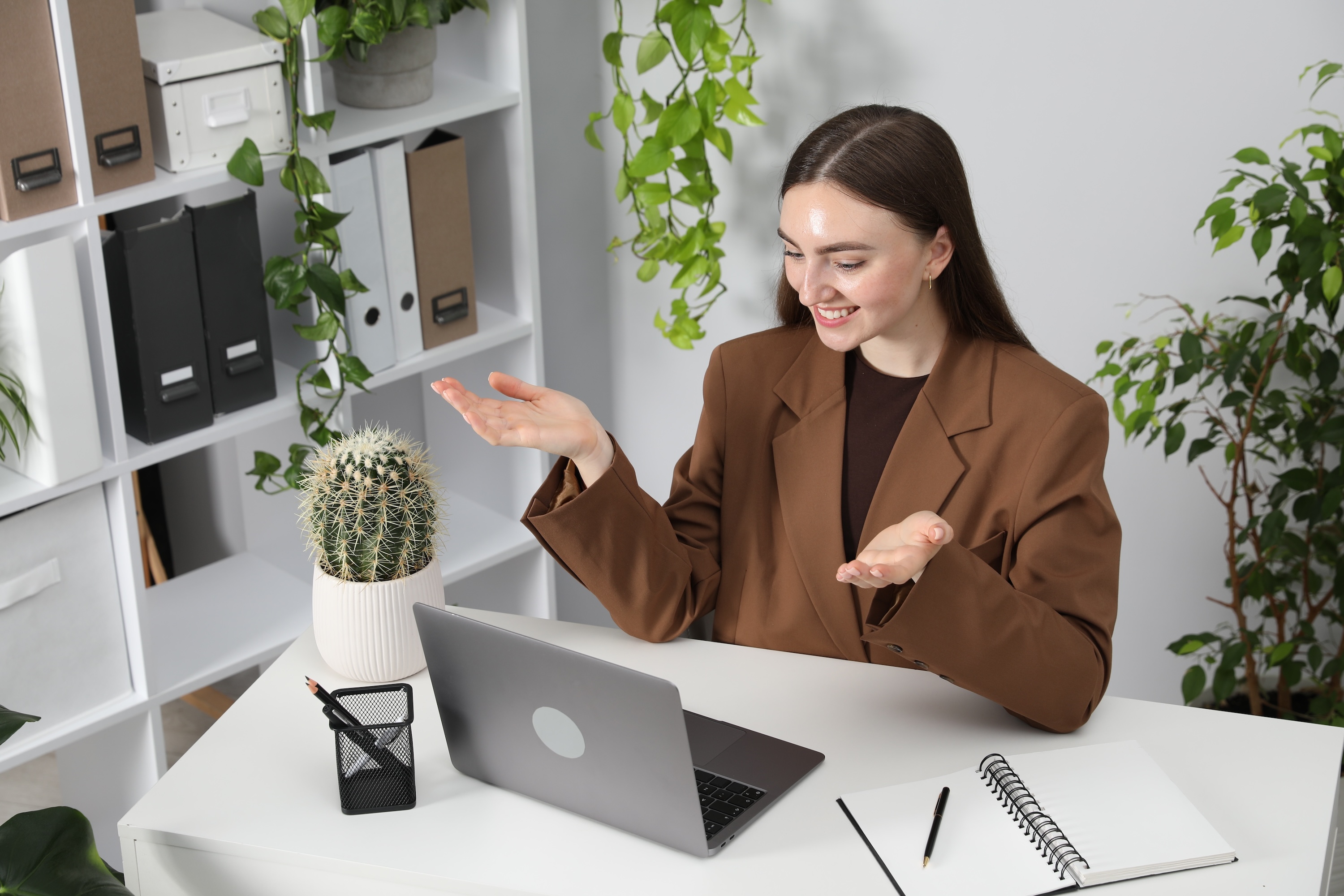 A smiling woman conducting a video call or presentation on her laptop in a bright home office, highlighting the excellent work-from-home capabilities at Wildcat Vista in Godley, TX.