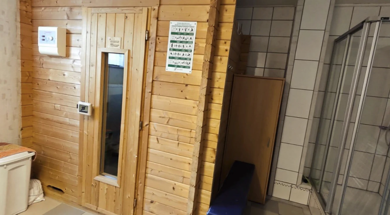 Alter Wäschekeller mit holzverkleideter Sauna und gefliestem Duschbereich vor der Neugestaltung