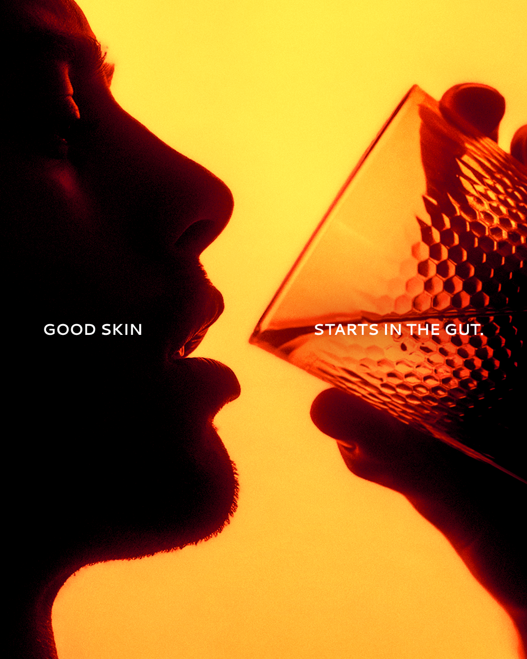 Person drinking from a textured glass in orange light