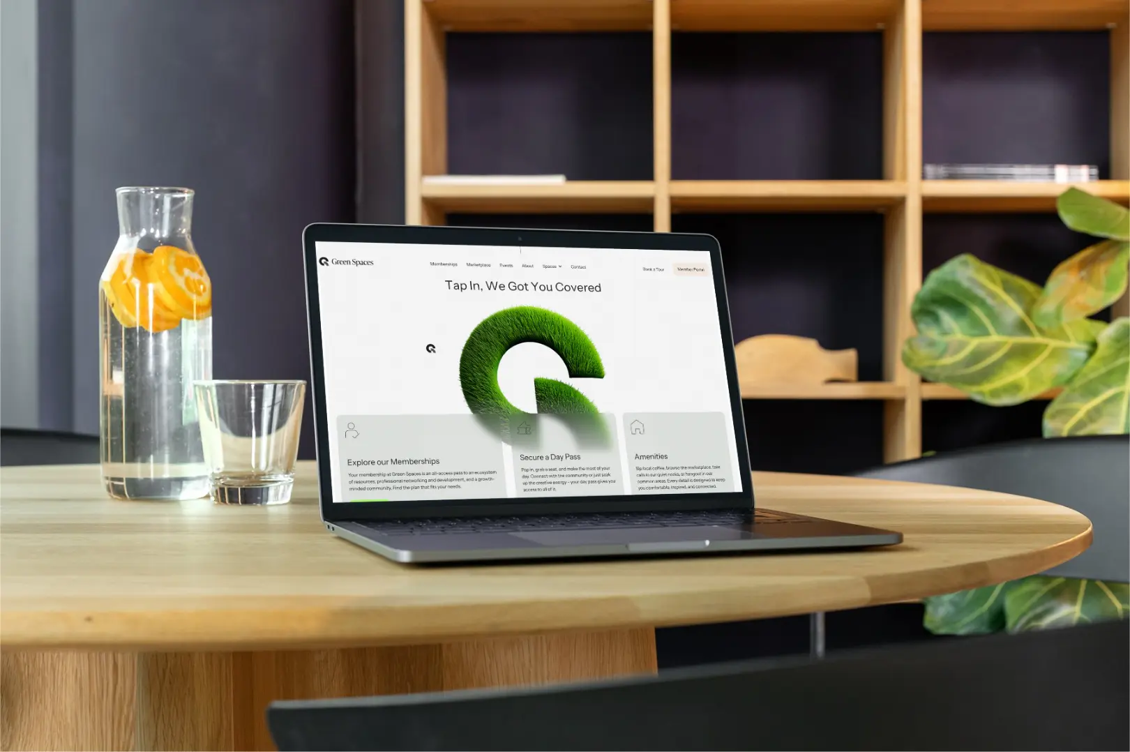 Laptop mockup of Green Spaces coworking website homepage on a wooden desk