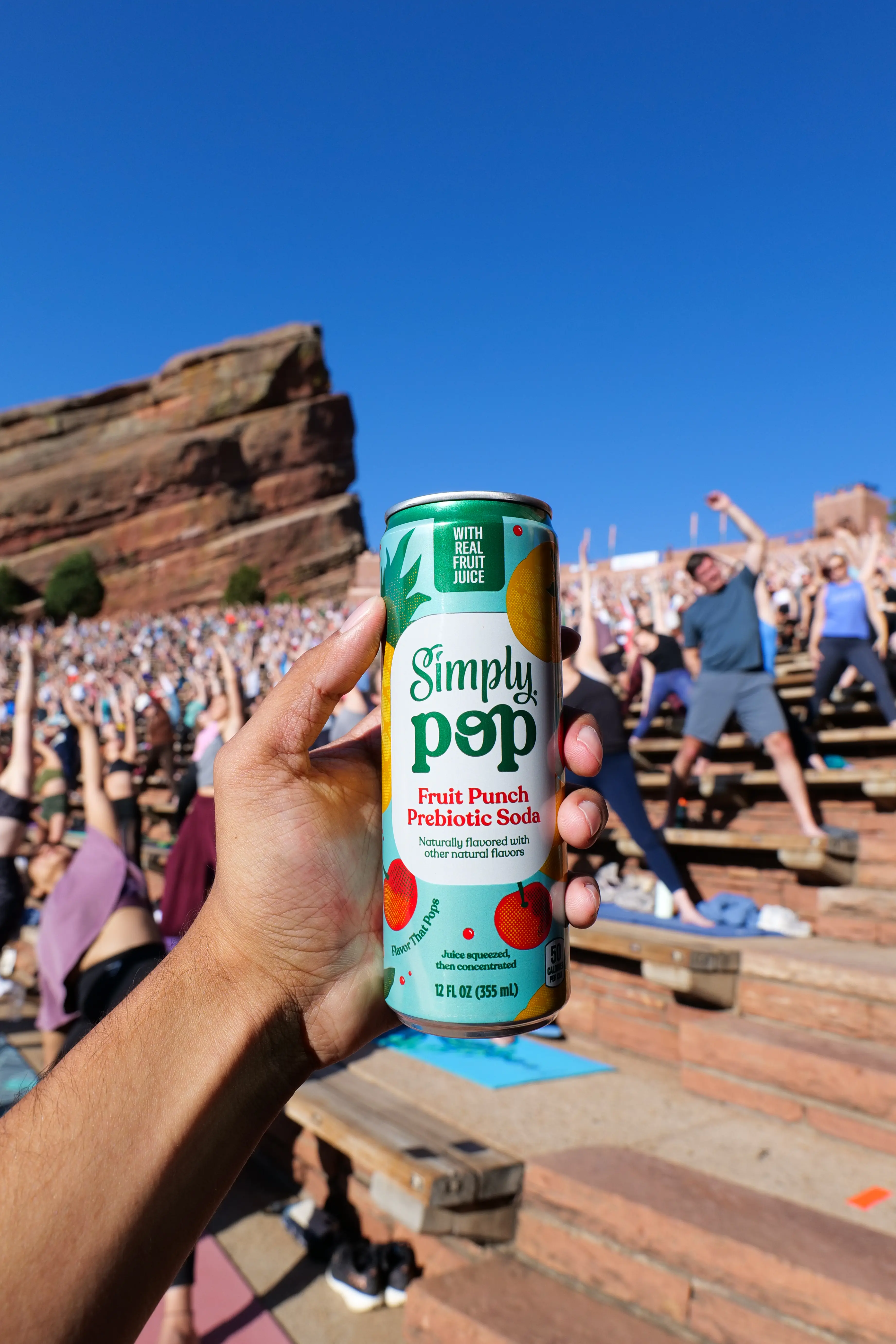 Hand holding Simply Pop fruit punch can at Red Rocks amphitheater yoga event