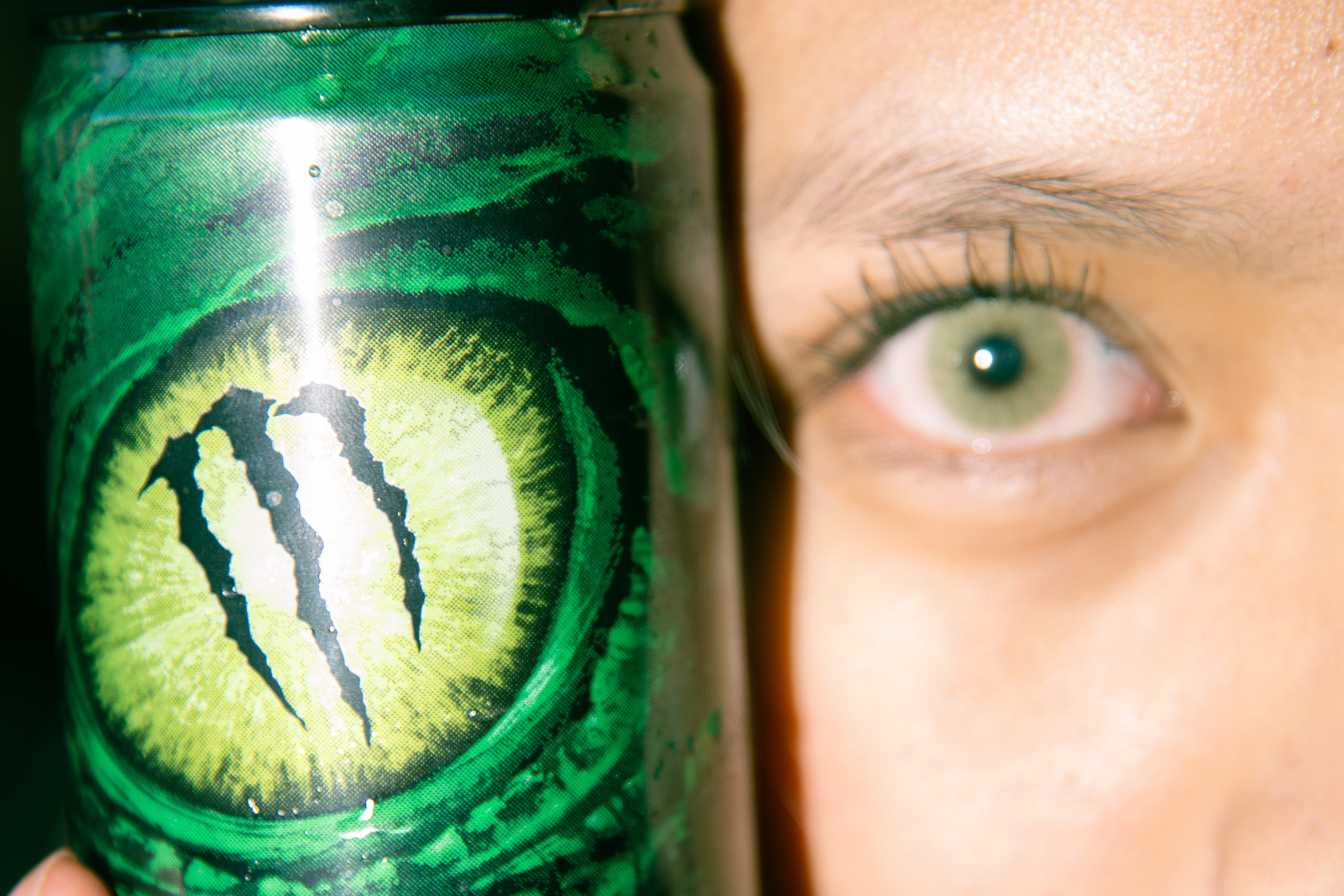 Split photo comparing Monster Energy eye graphic on can with a matching human eye