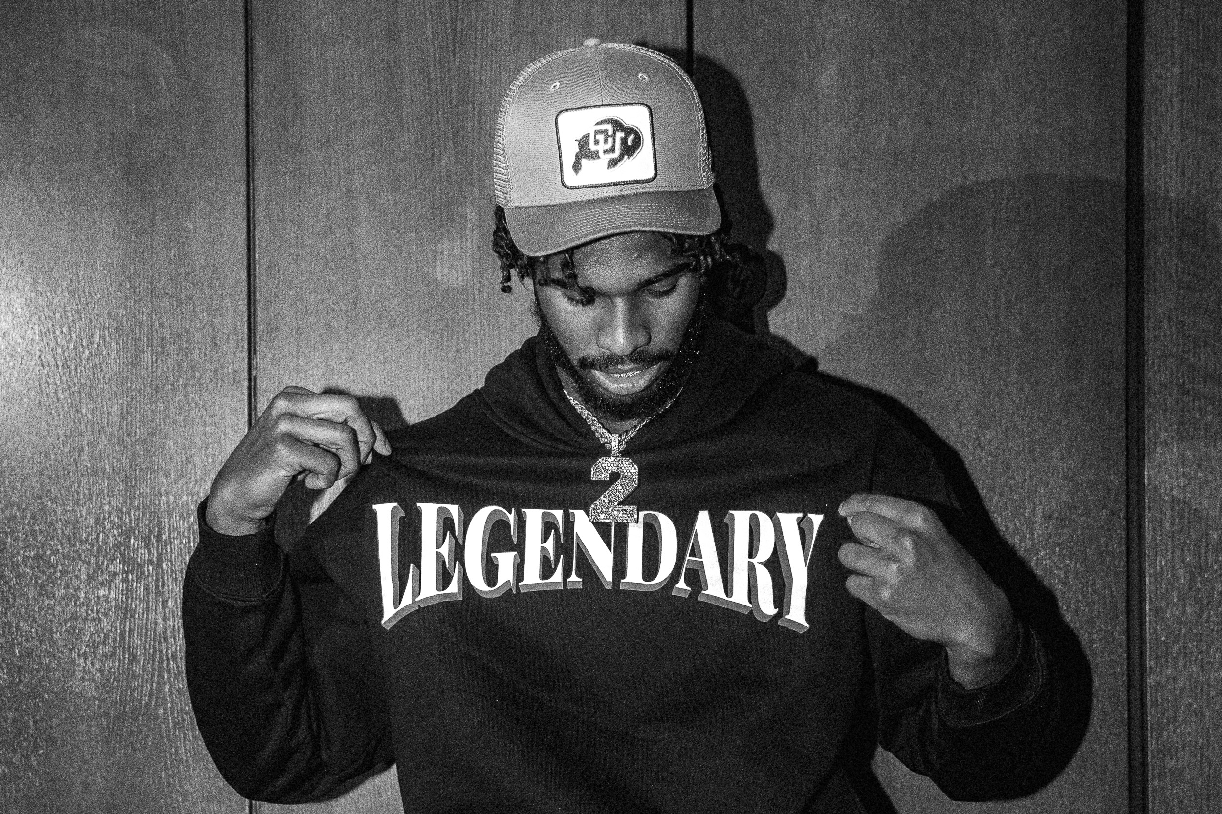 Black-and-white portrait of athlete in CU hat and Legendary hoodie with diamond number-2 chain