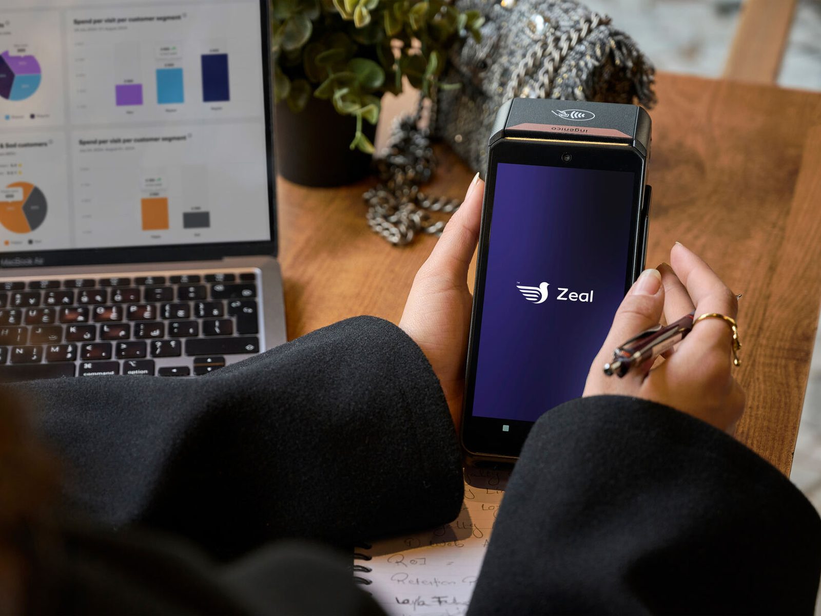 Woman holding payment terminal Zeal logo screen laptop analytics