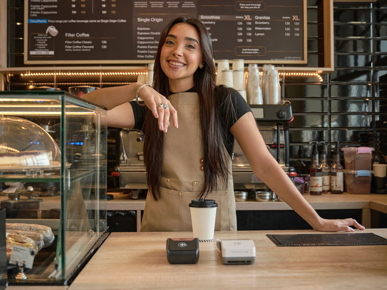 Barista smiling apron cafe counter payment terminals menu board