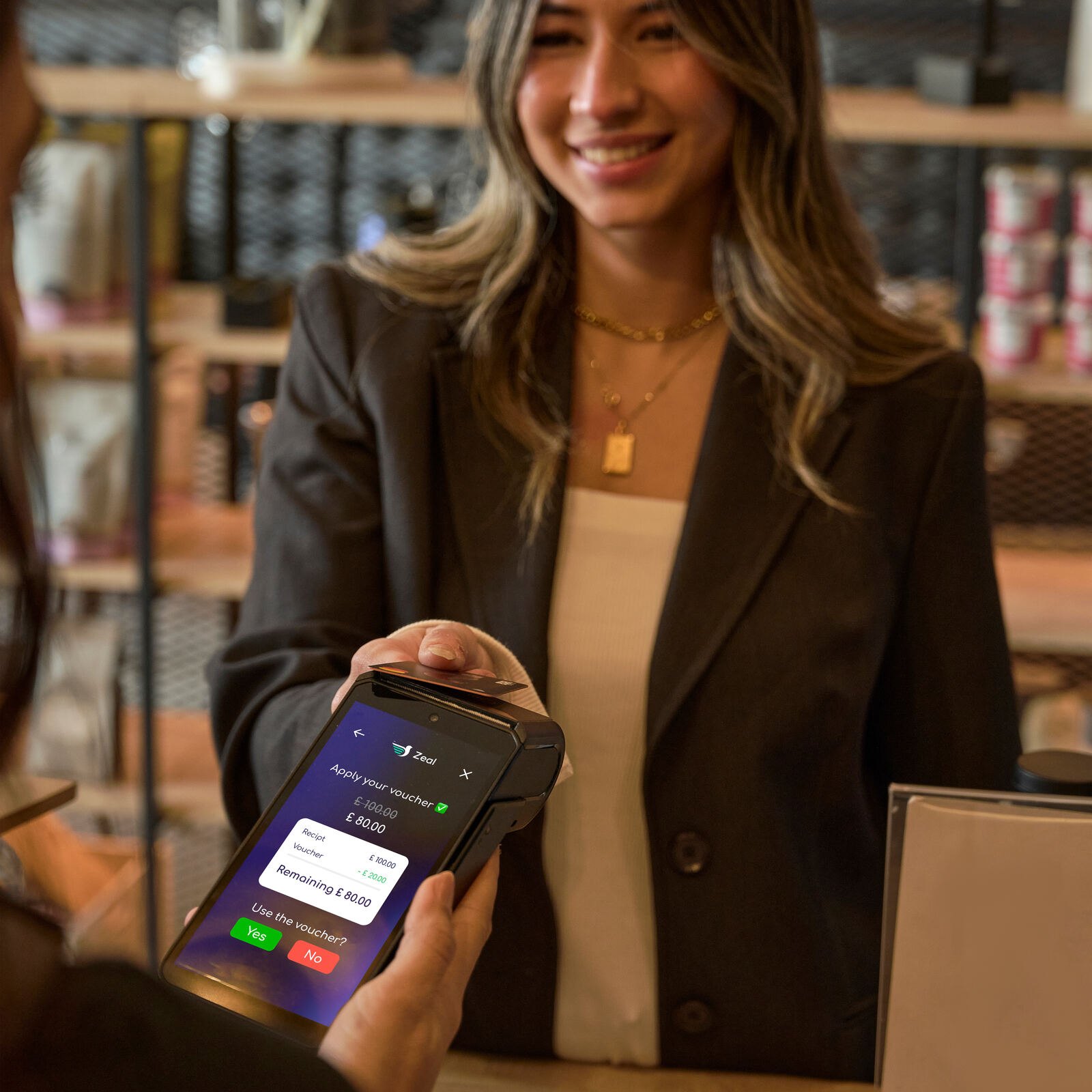 Staff member showing a voucher on a Zeal payment terminal in a restaurant