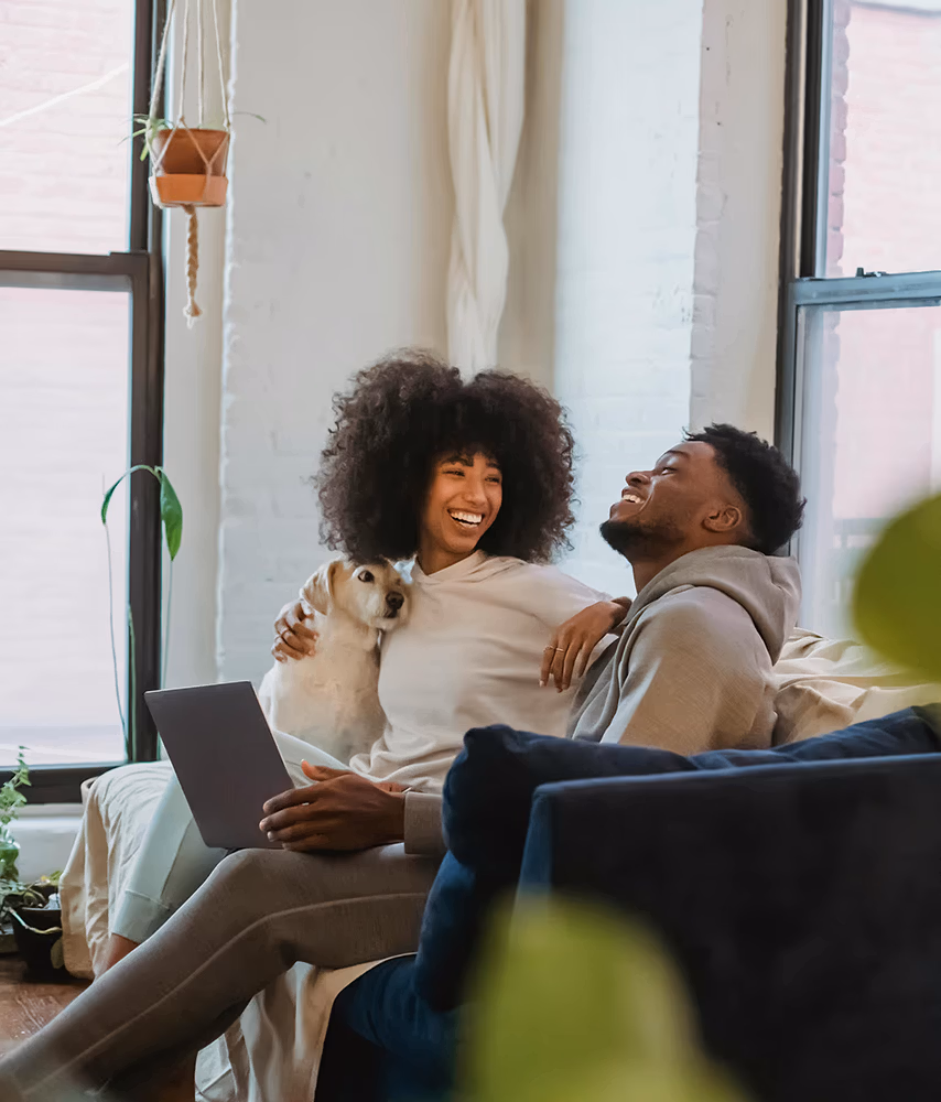 Young couple sitting on the couch with their dog
