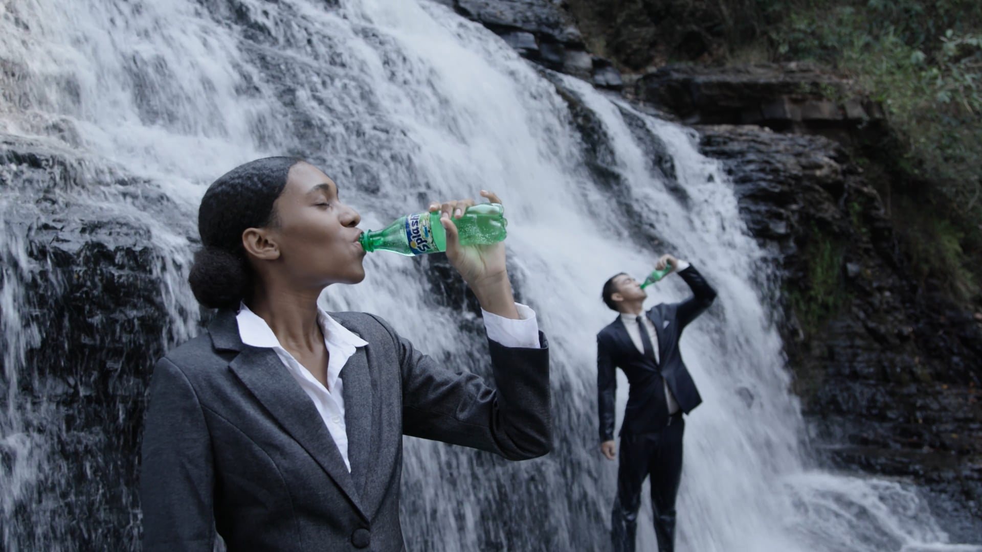 Two people in suits at a waterfall