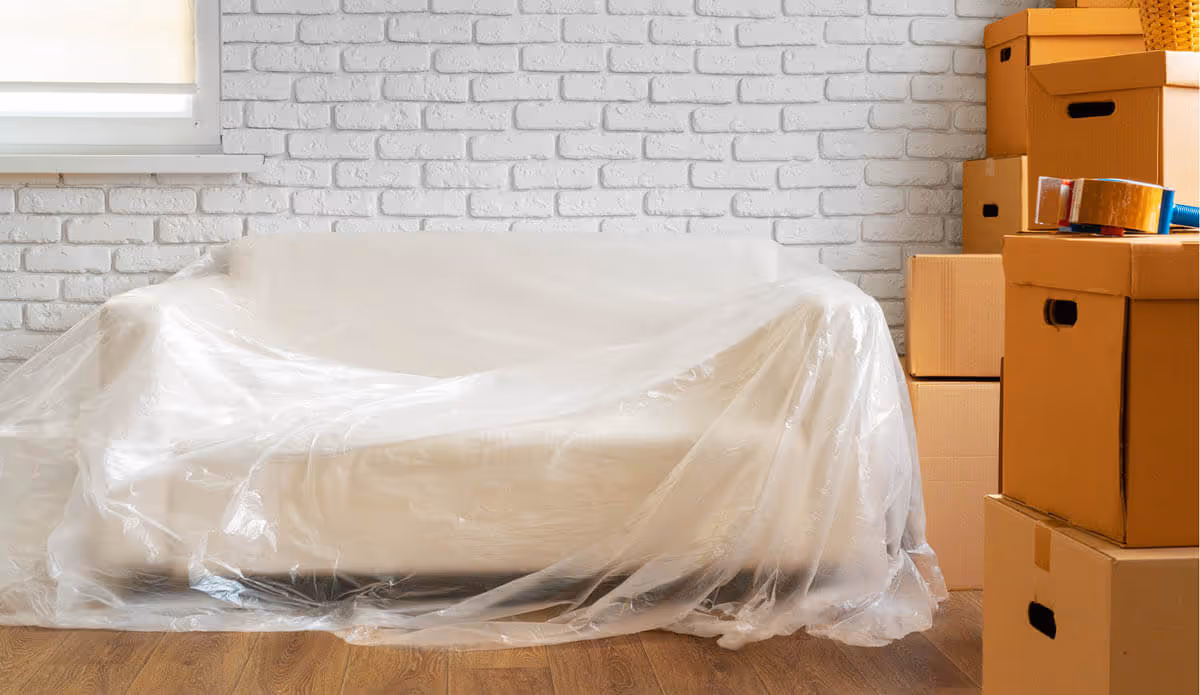 Picture of a elegant white couch wrapped in thick plastic ready to be packed and shipped state to state.