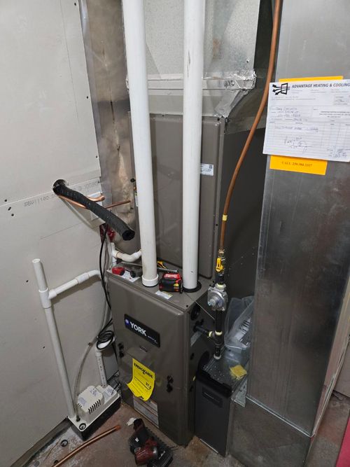 A furnace and ductwork installed in a basement, along with an on-demand water heater, providing efficient heating, cooling, and hot water for the home.