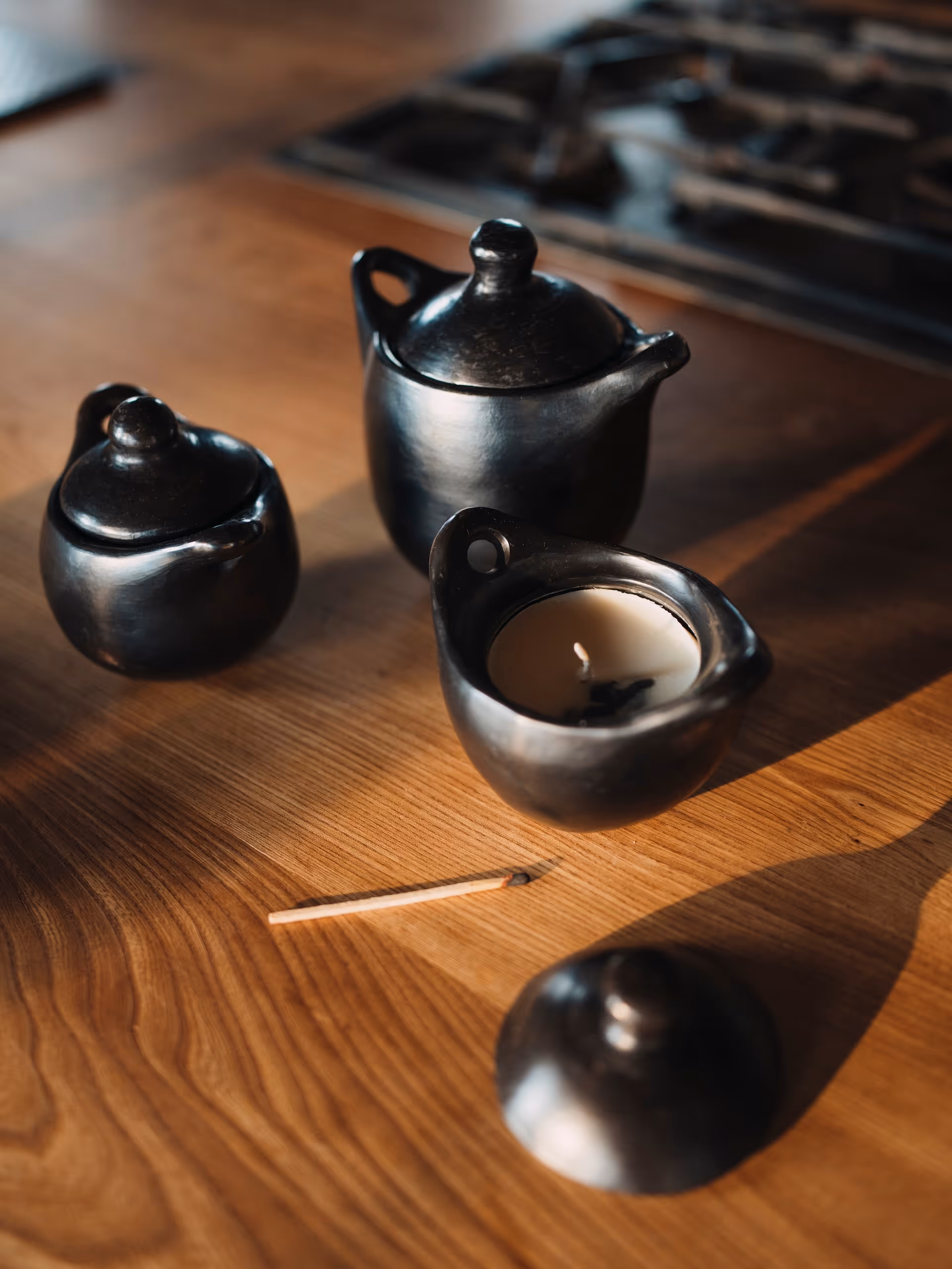 Handmade artisan pots with candles on a wooden table in soft natural light.