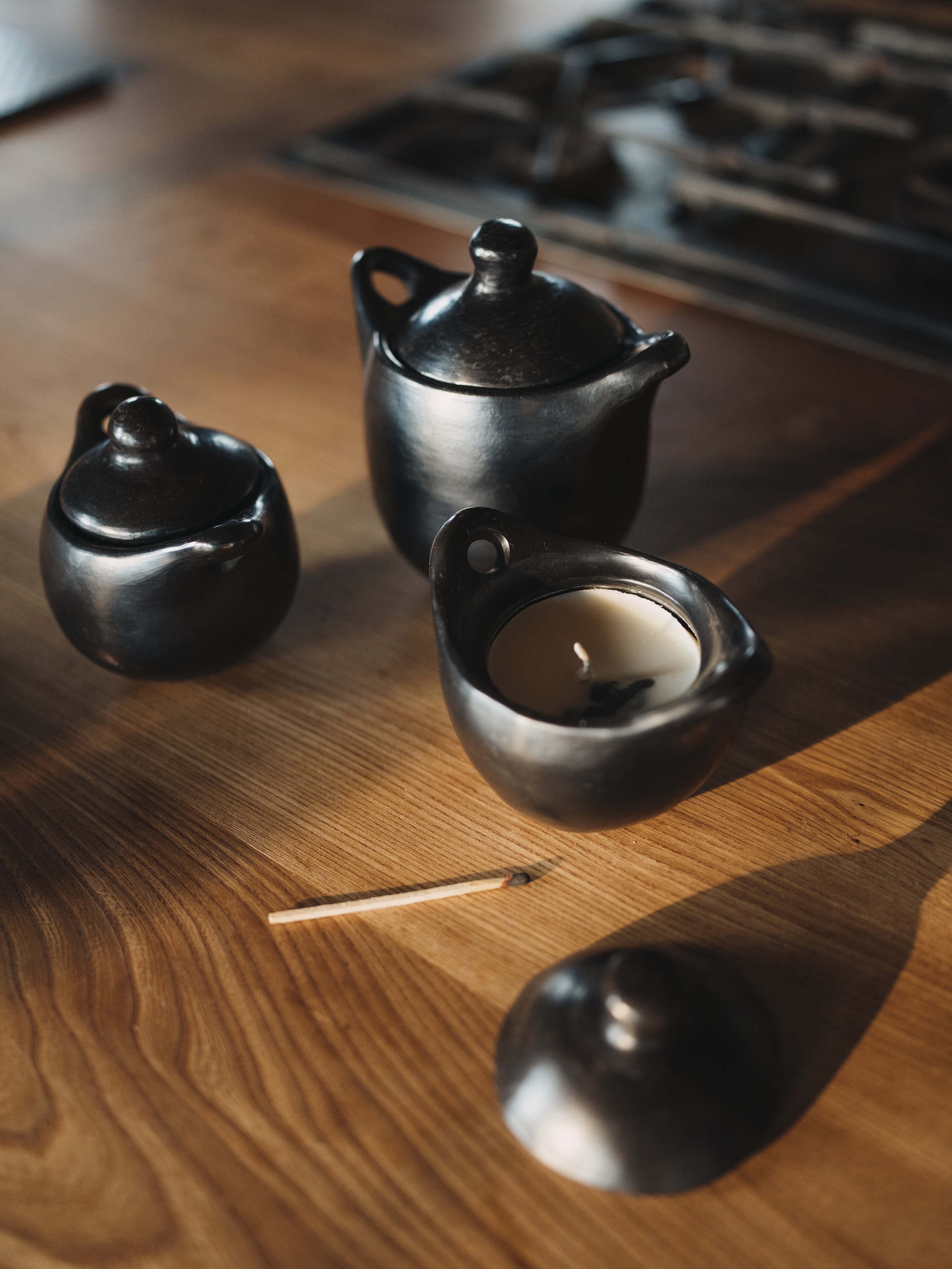 Handmade artisan pots with candles on a wooden table in soft natural light.