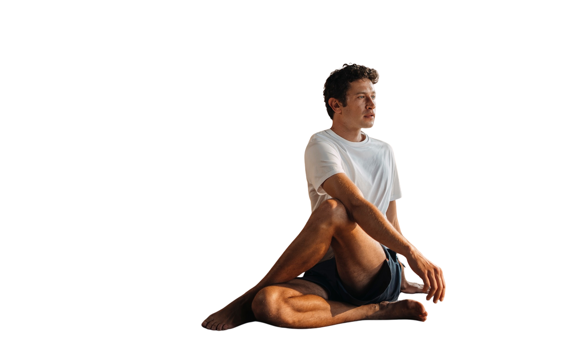 Man sitting cross-legged wearing a white Chirimoya Classic Pima cotton T-shirt and navy shorts.