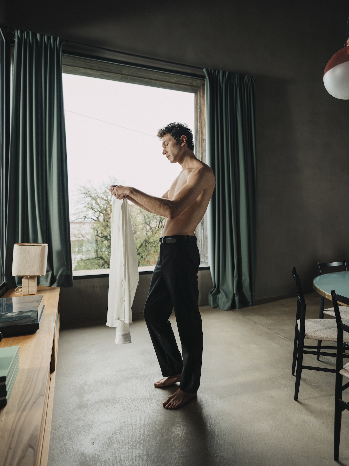 Man stretching in morning light wearing a white Chirimoya Natural Dye Pima dress shirt.