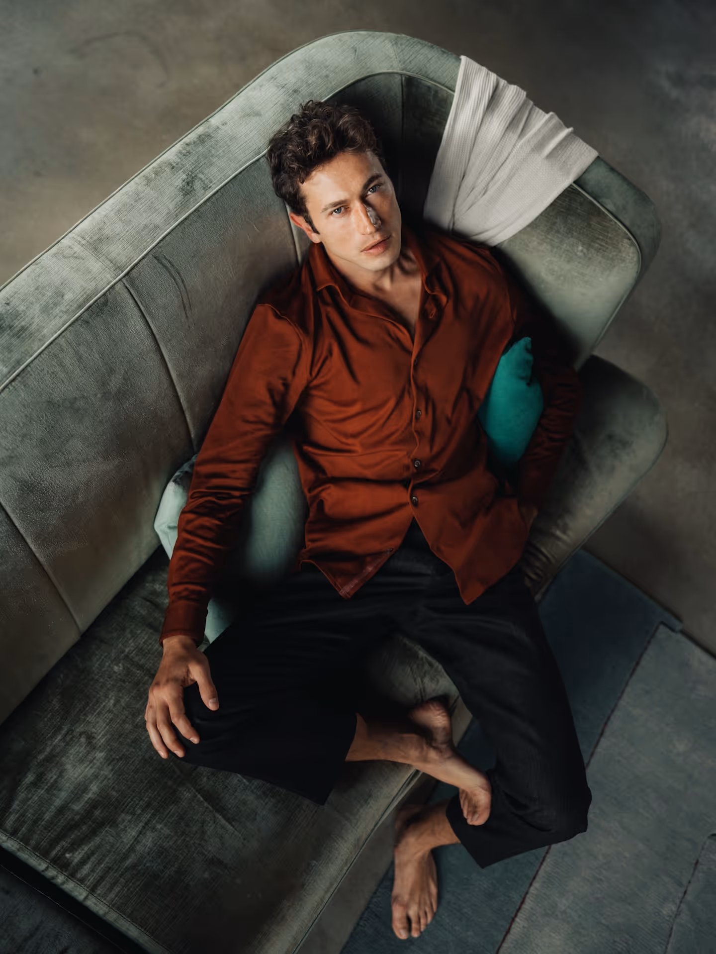 Man reclining on a sofa wearing a mahogany Chirimoya Natural Dye long Pima shirt.