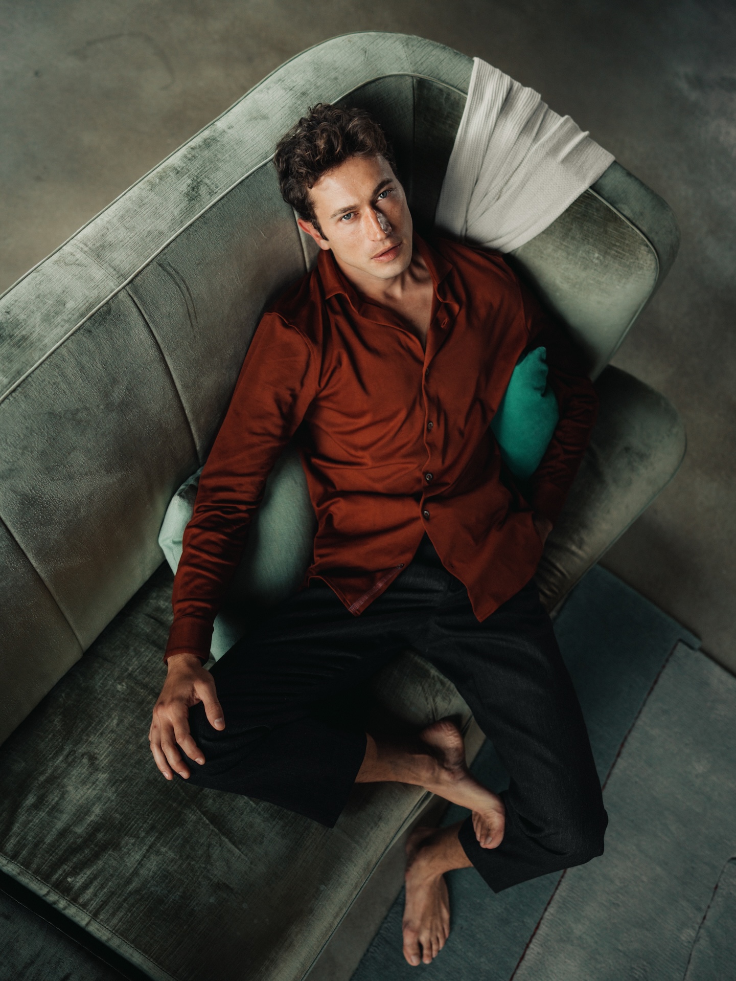 Man reclining on a sofa wearing a mahogany Chirimoya Natural Dye long Pima shirt.