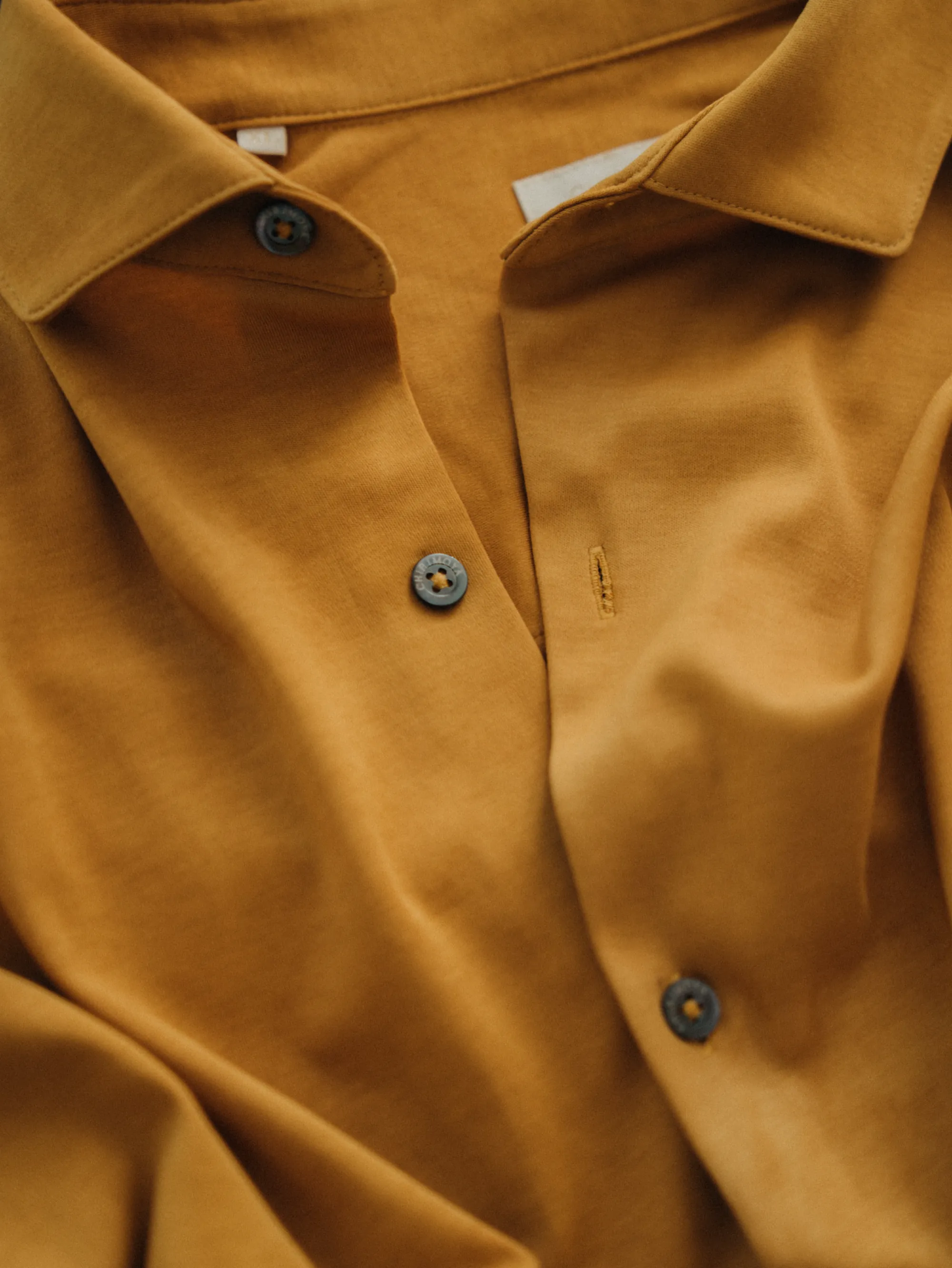 Close-up of a mustard-yellow shirt collar and buttons