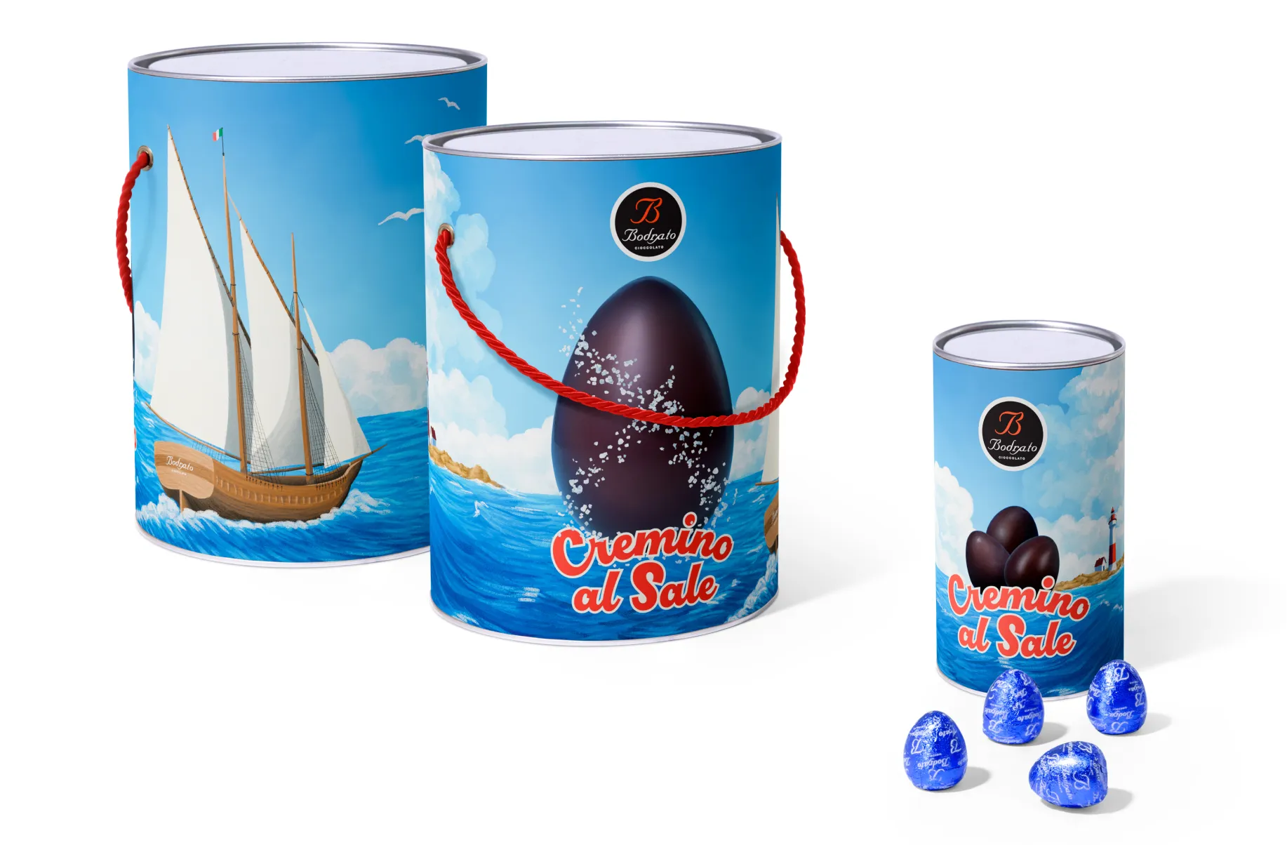 Three cylindrical Bodrato "Cremino al Sale" chocolate eggs tubes in two sizes, featuring a nautical illustrated label with a sailboat, ocean waves, and a dark chocolate egg emerging from the sea. A small standalone tube and four blue foil-wrapped chocolate eggs are arranged to the right.