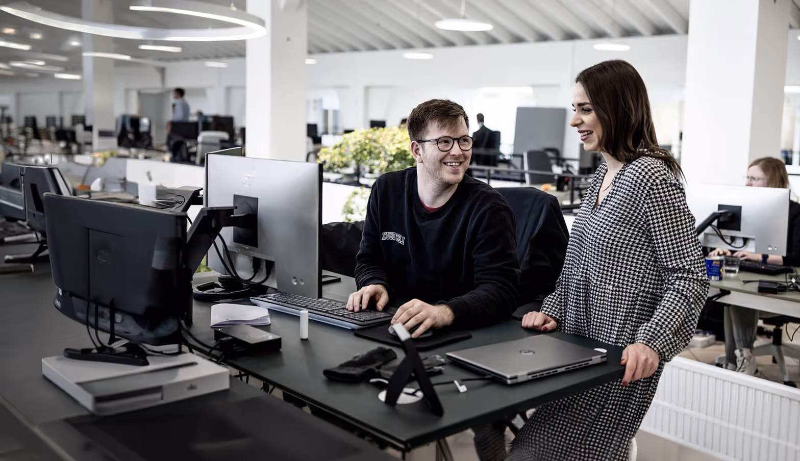 Male and female cBrain employees in conversation in front of a computer screen