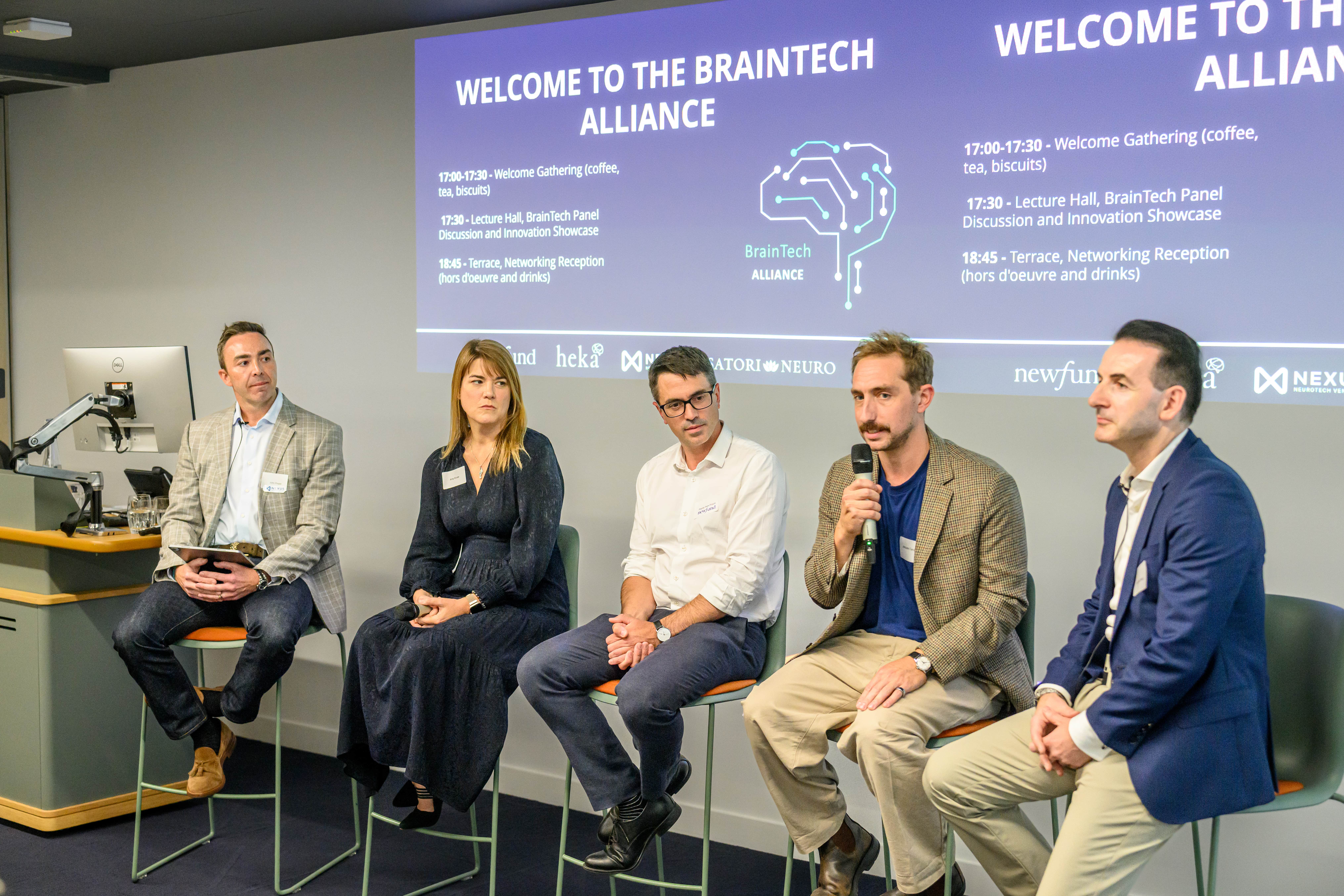 4 men and a women in a Panel discussion in front of a sign "Welcome to the BrainTech Alliance"