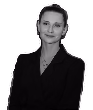 Black and white portrait of a woman with hair tied back, wearing a dark blazer and necklace.