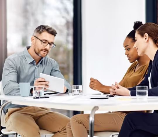 A man displays something interesting to two women on a digital tablet