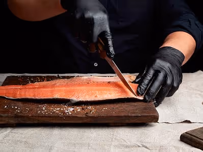 Chef traiteur découpant un saumon frais pour un service buffet ou cocktail dînaé.
