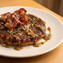 Tatin d'échalotes caramélisées dressée en assiette, spécialité maison du traiteur Goulu.