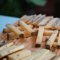 Assortiment de fromages en bâtonnets disposés sur une planche en bois.